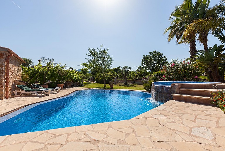 Poolterrasse Sonnenliegen Rasen Natursteinmauer Palmen