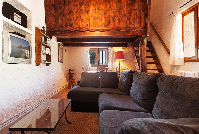 Wohnzimmer Sofas Couchtisch Fernsehgeraet Musikanlage Spinnrad Stehlampe Holztreppe Fenster