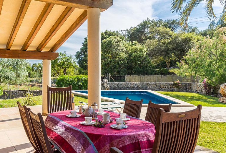 Terrasse Gartentisch Stühle Geschirr Tischdecke Pool Büsche 