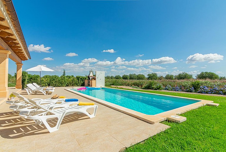 Sonnenliegen am Poolbereich vor der Finca mit Rasenfläche und Schwimmbecken