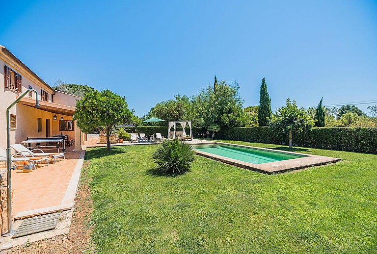 Außenbereich mit Pool vor der Finca im Garten mit Rasen