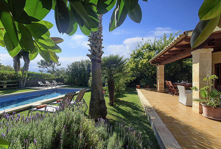 Poolbereich vor der Finca im Garten mit Rasen und Bäumen