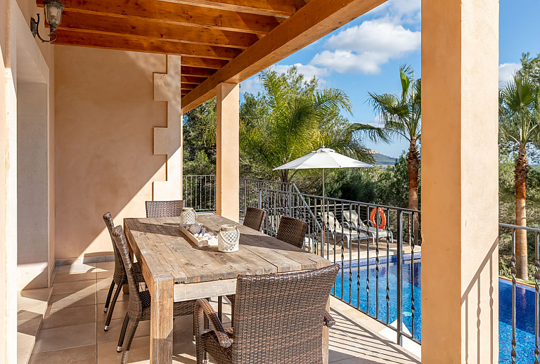 Terrasse mit Esstisch und Poolblick