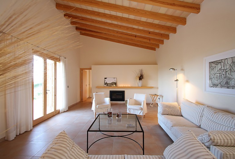 Wohnzimmer Sofas Glastisch Kamin Holzbalken Terrassentuer