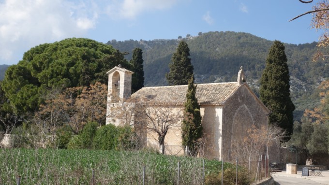 Kirche mit Bäumen und Bergen dahinter